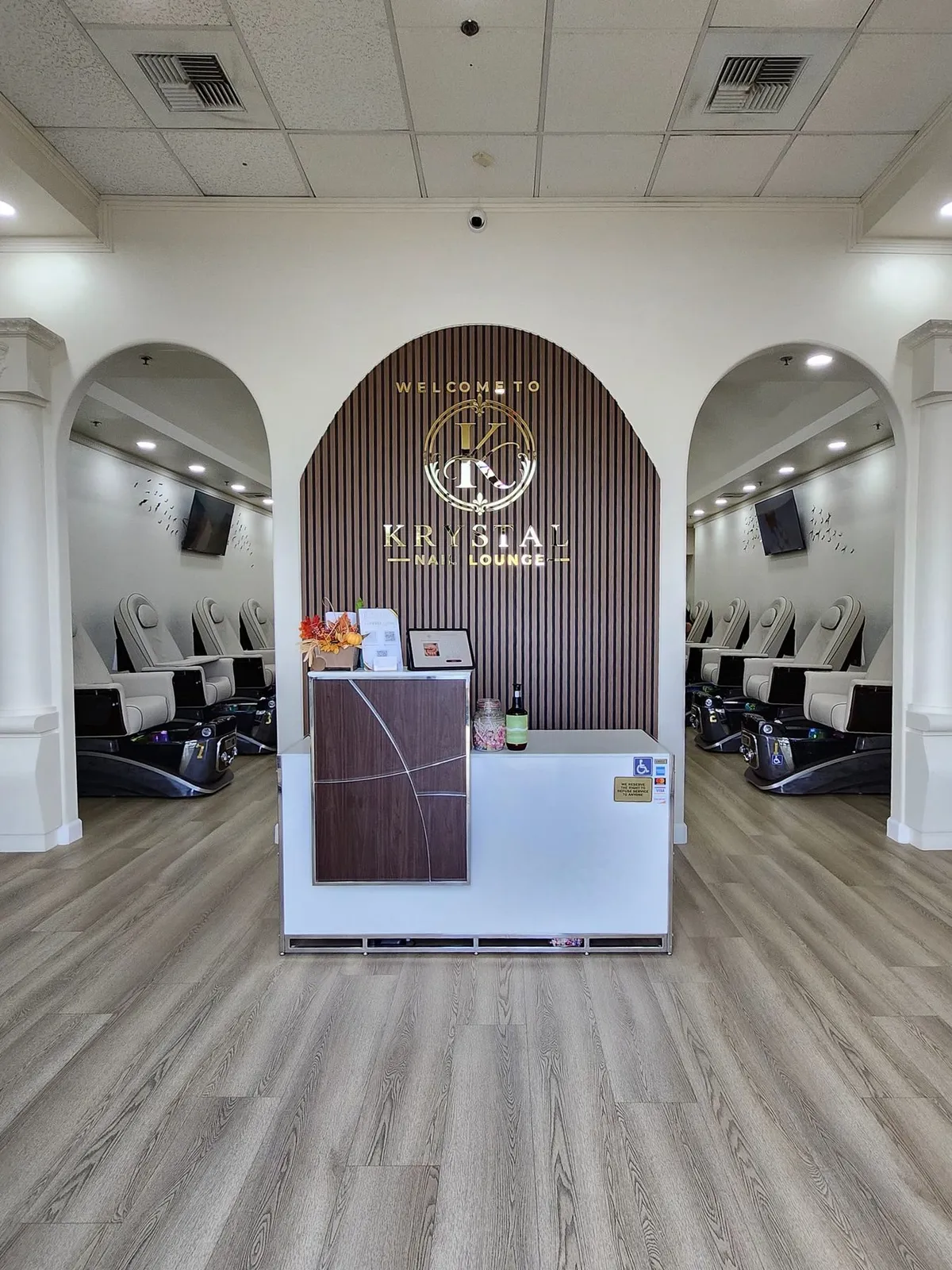 Reception desk in front of the gold Krystal logo sign on a slatted walnut arch