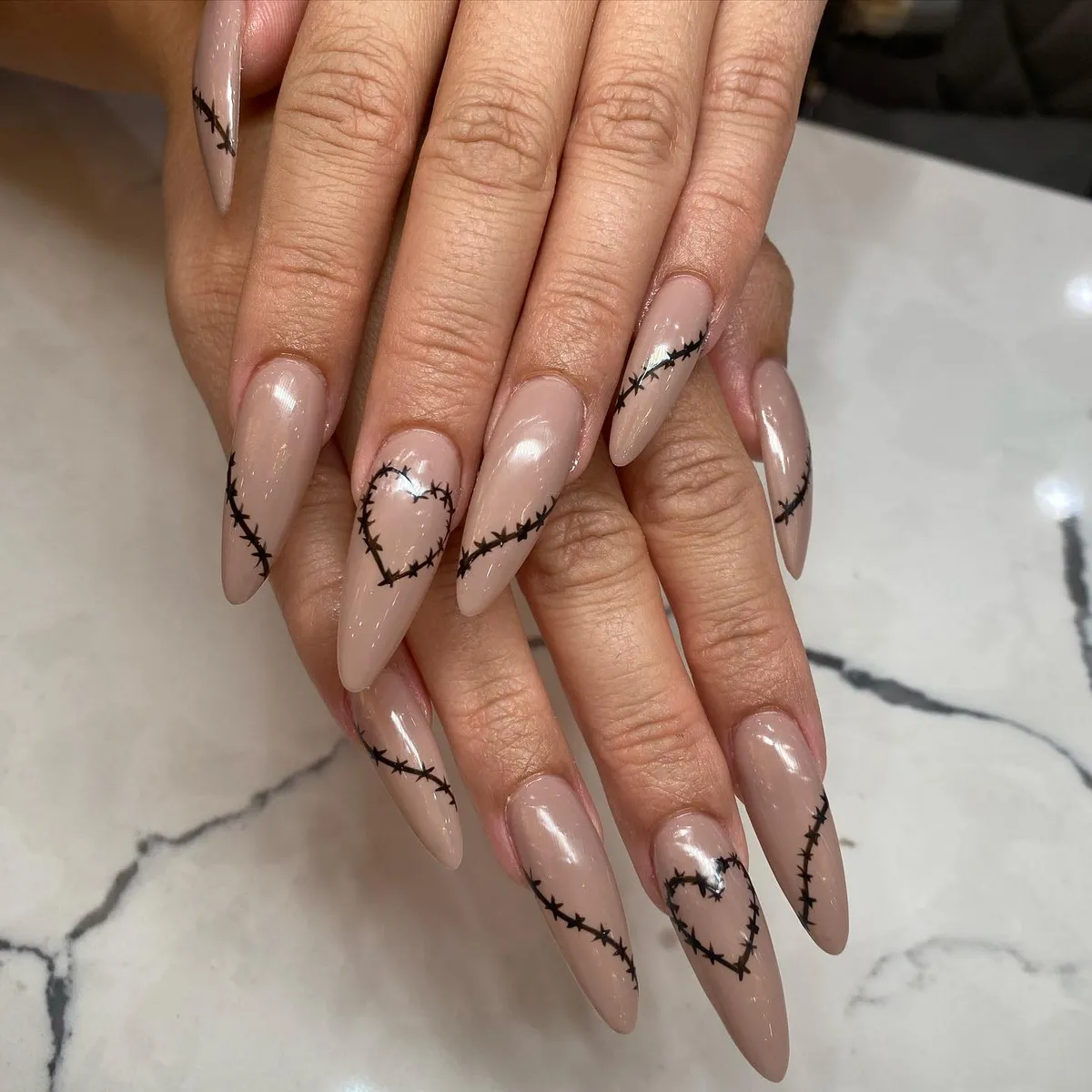 Long almond nude nails with hand-painted black thorn hearts
