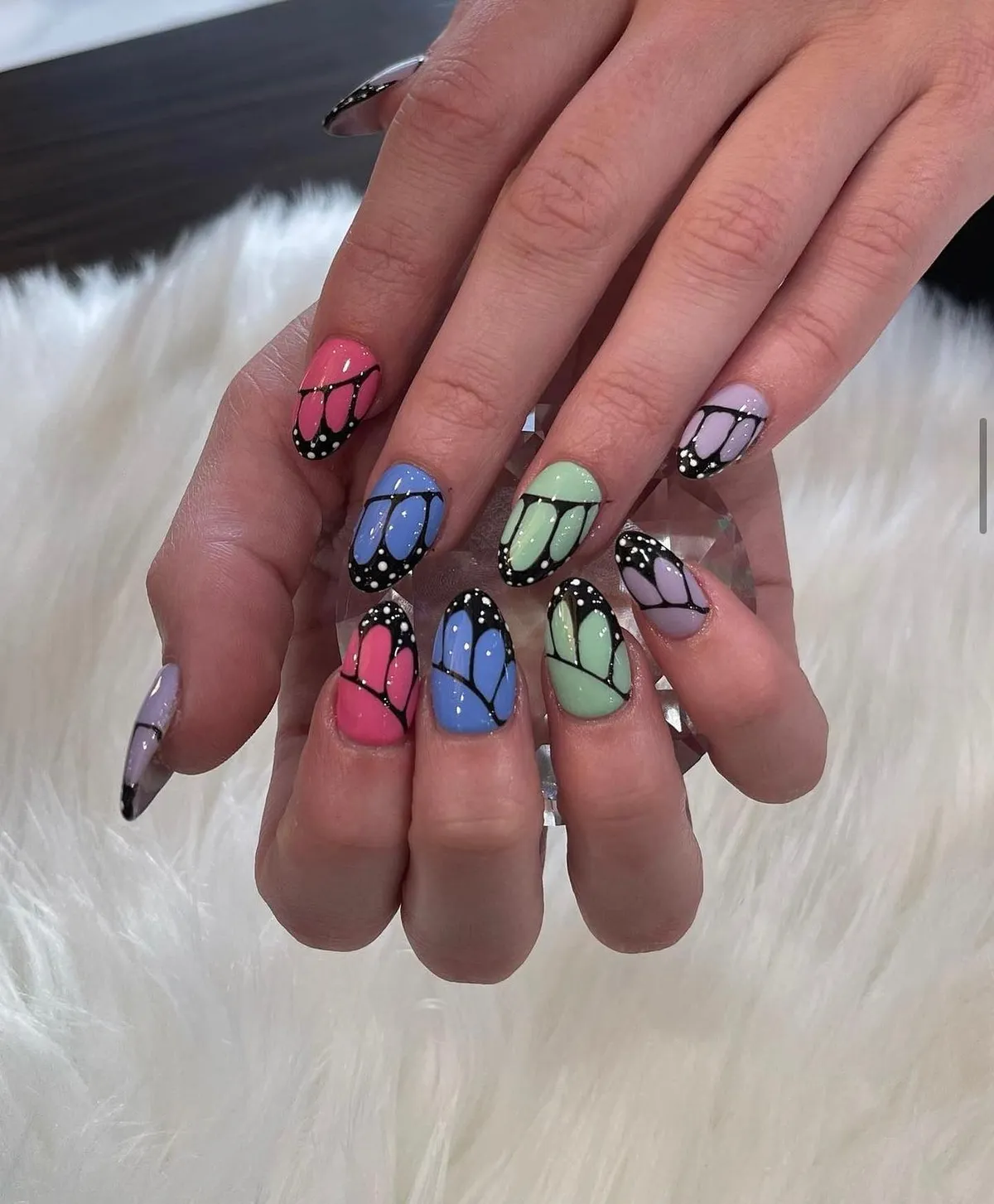 Pastel butterfly-wing nail art in pink, blue, green and lilac