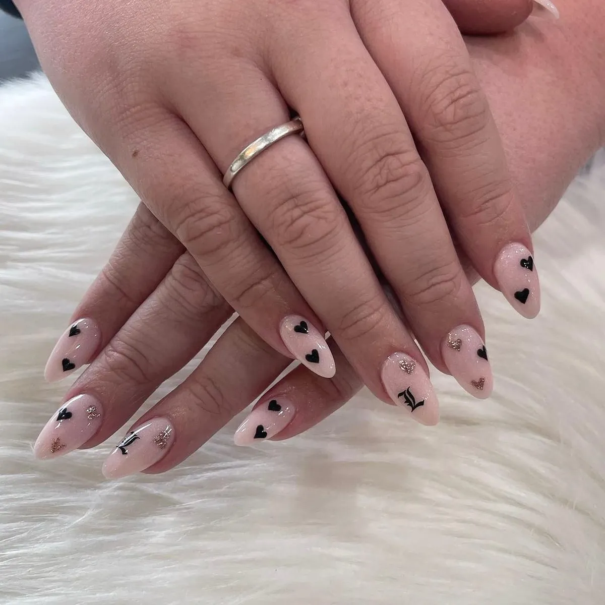 Sheer pink almond nails with black and gold glitter hearts