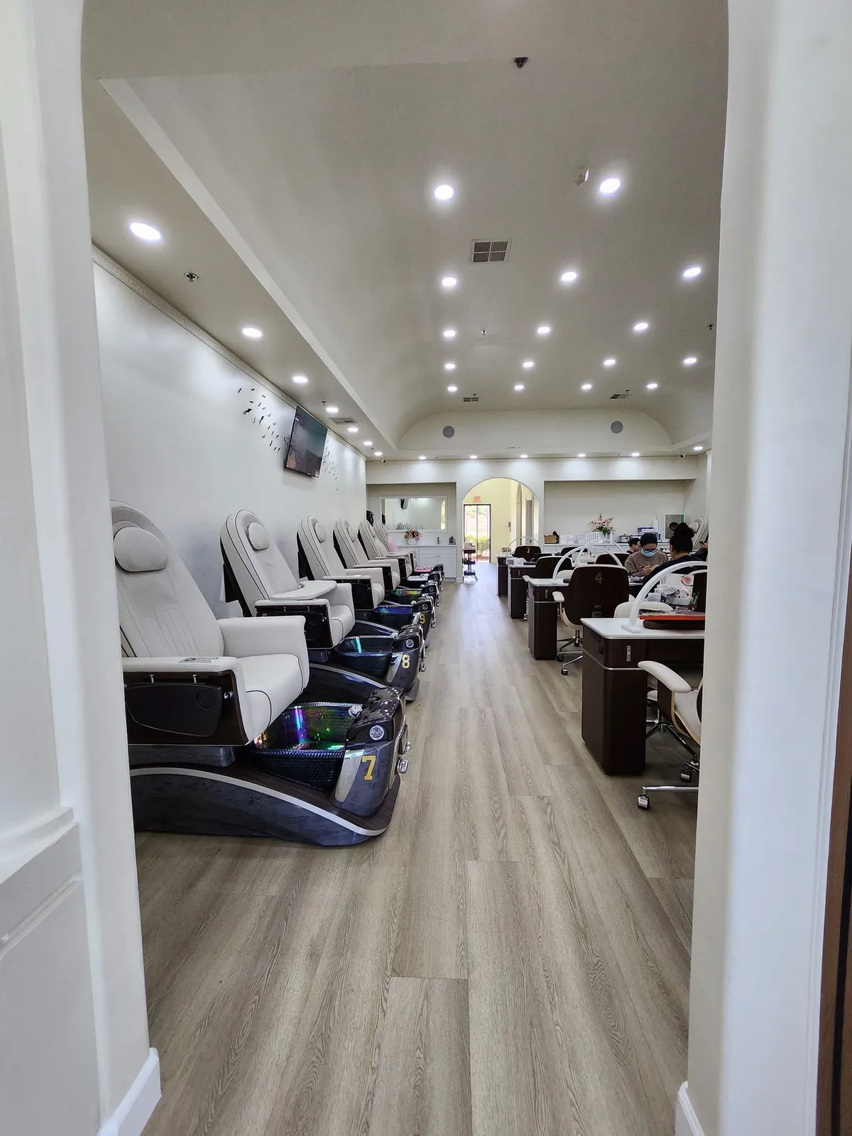 Row of cream leather massage pedicure chairs under an arched doorway