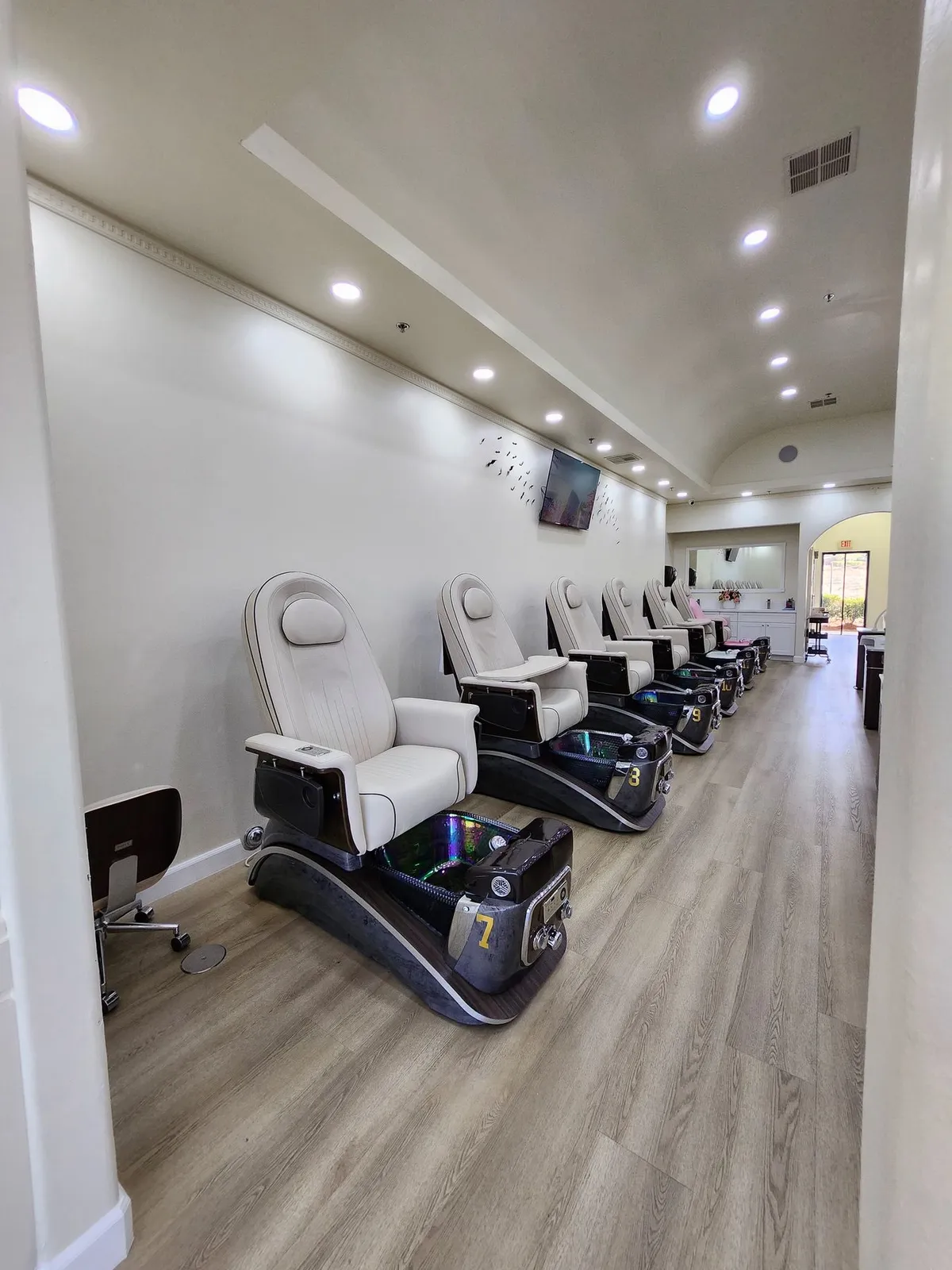 Pedicure chairs with glass basins along a bright wall
